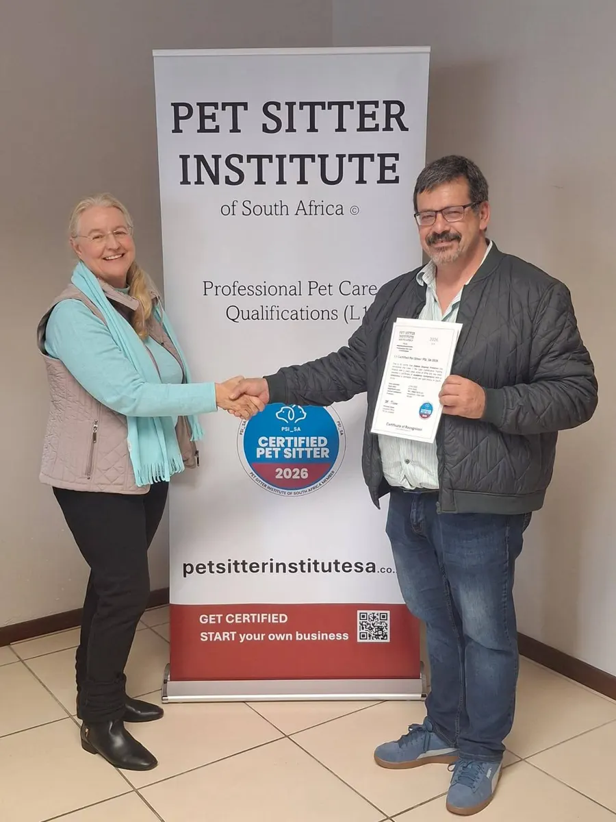 A newly certified PSI SA pet sitter receiving his certificate in front of a Pet Sitter Institute banner