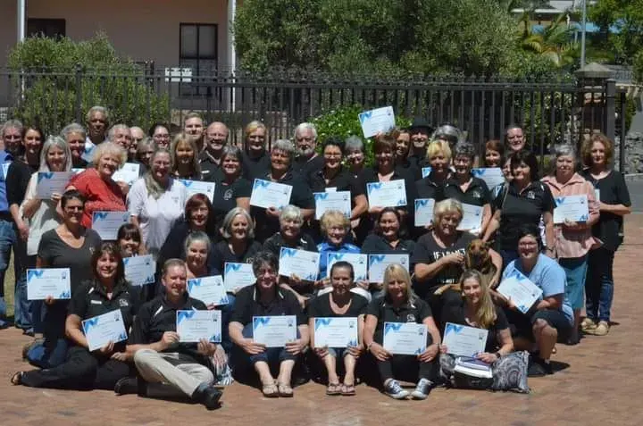 A large group of pet sitters holding their certificates after completing training